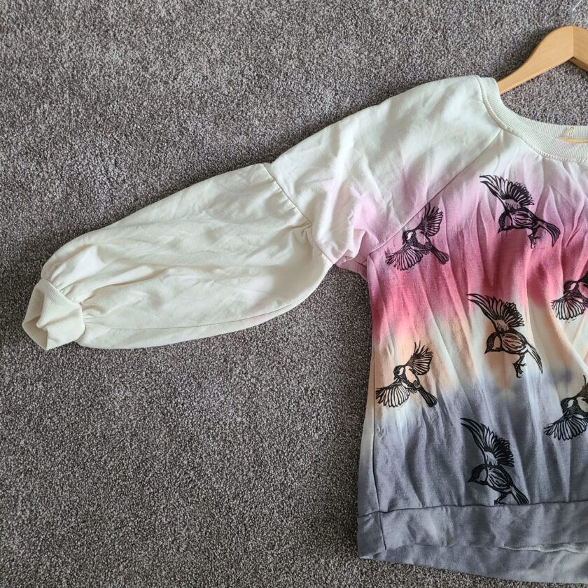 a white and pink shirt with birds on it.