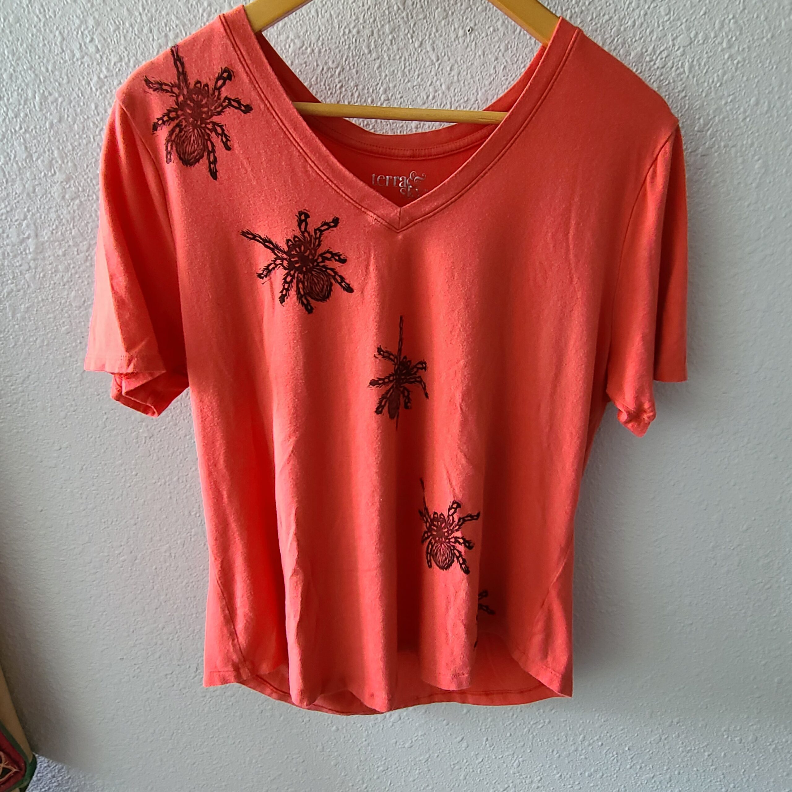 an orange t - shirt with spiders on it.