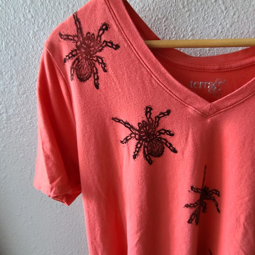 an orange t - shirt with black spiders on it.