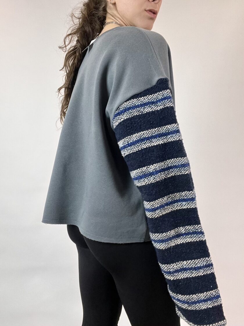 a woman wearing a sweater with a striped sleeve.