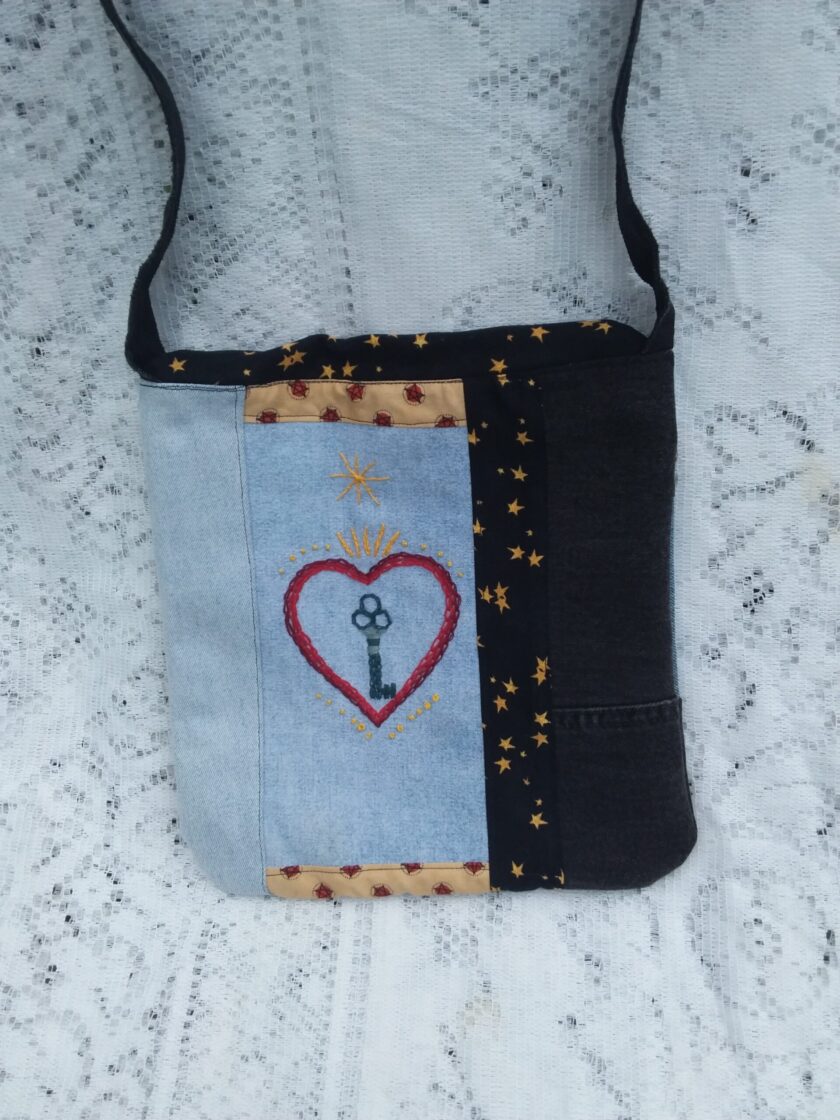 Eco-fashion designer handbag of denim and vintage textiles with artisan embroidered focal piece