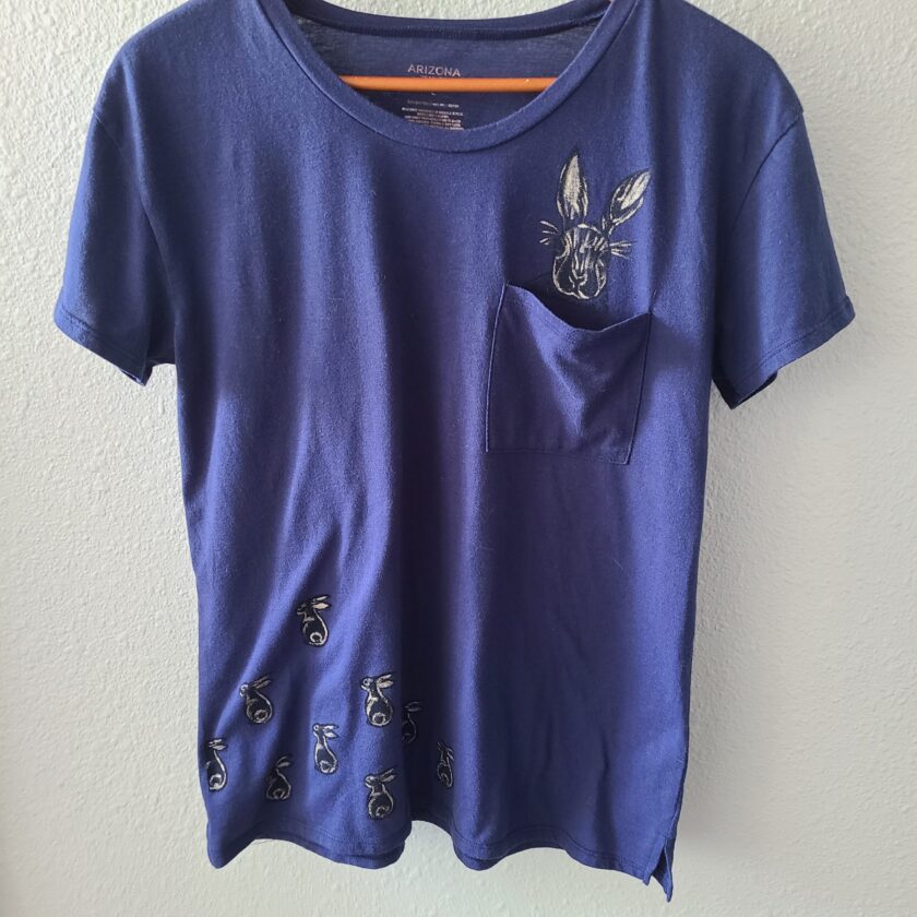 a blue t - shirt with a pocket on it.