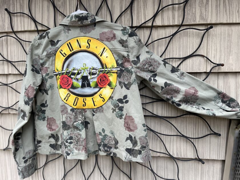 a shirt with a guns and roses logo hanging on a wall.