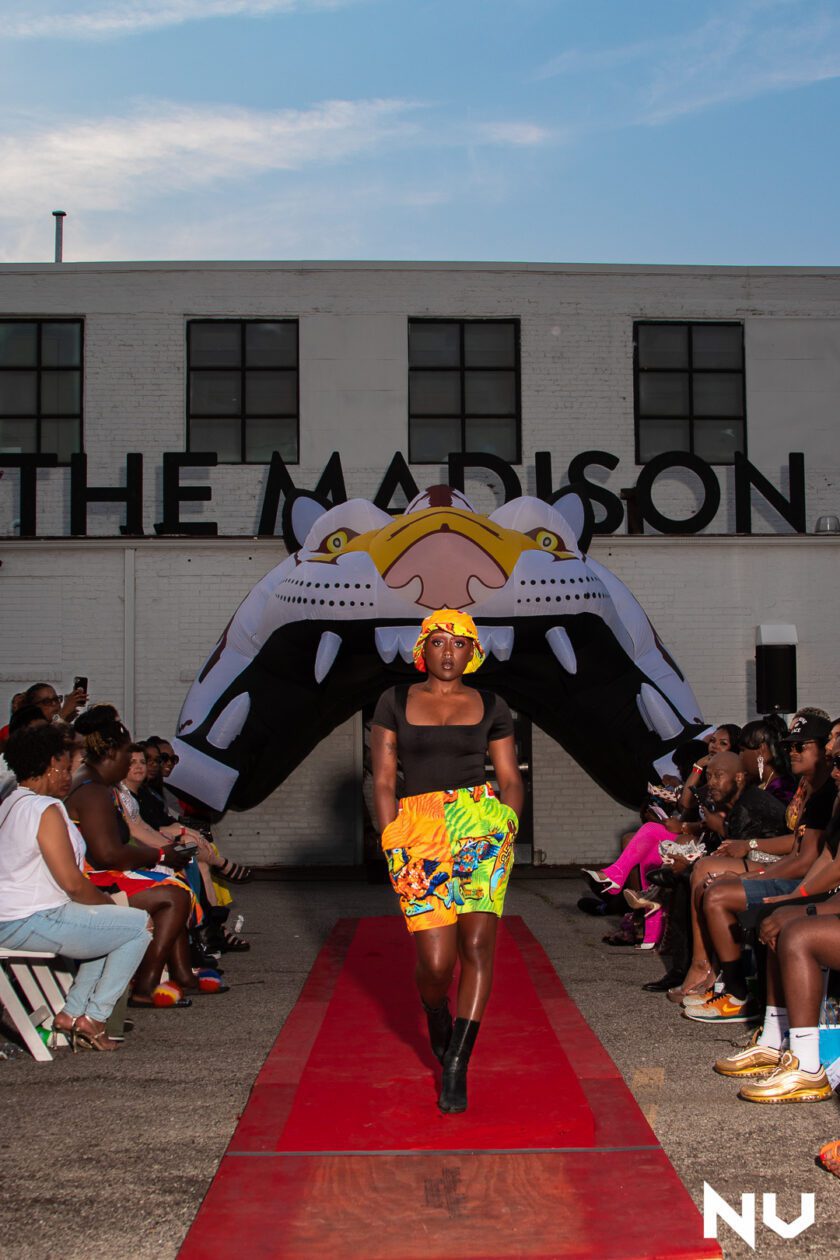 a woman walks down the runway at the madison fashion show.