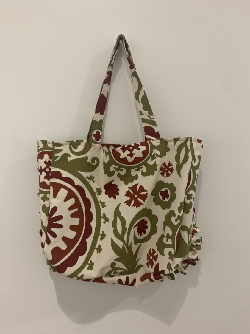 a green and red tote bag hanging on a wall.