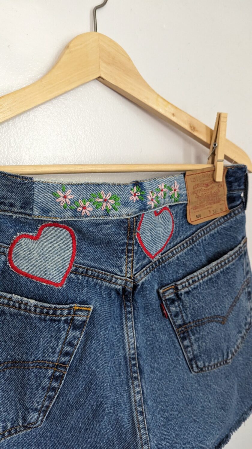 a pair of denim shorts with hearts embroidered on them.
