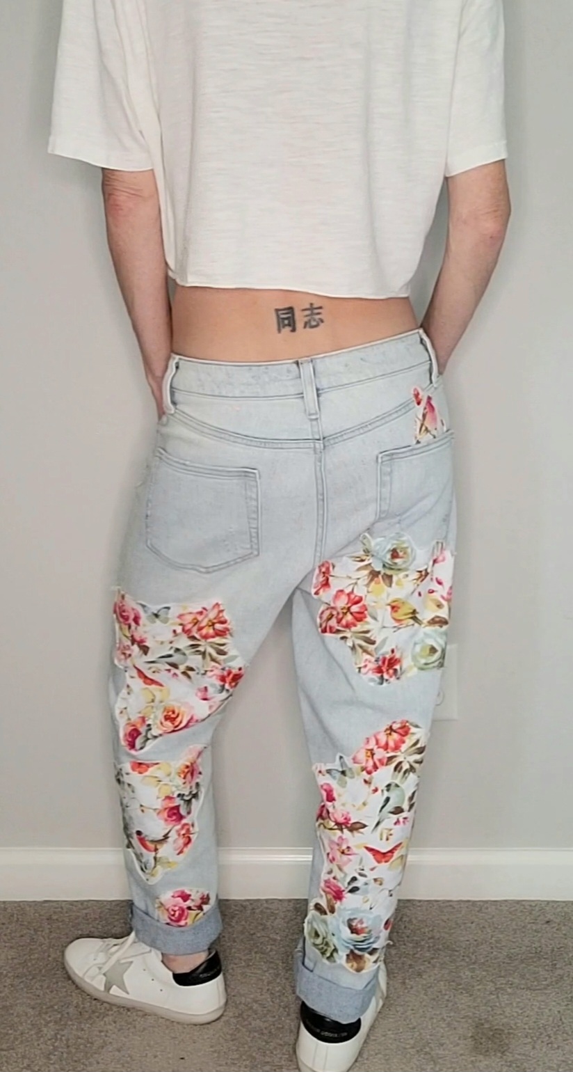 the back of a woman wearing floral printed jeans.