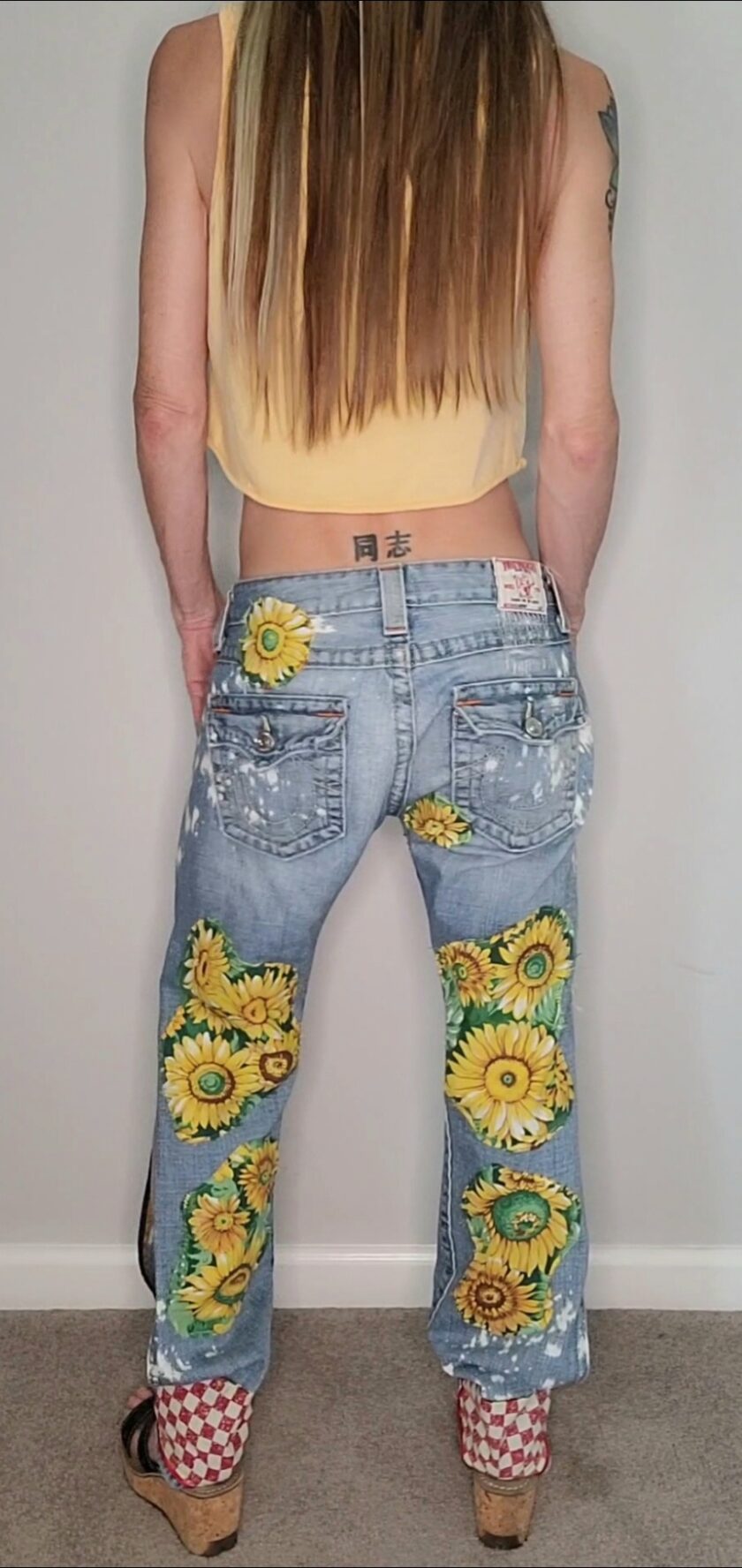 a woman wearing a pair of jeans with sunflowers on them.
