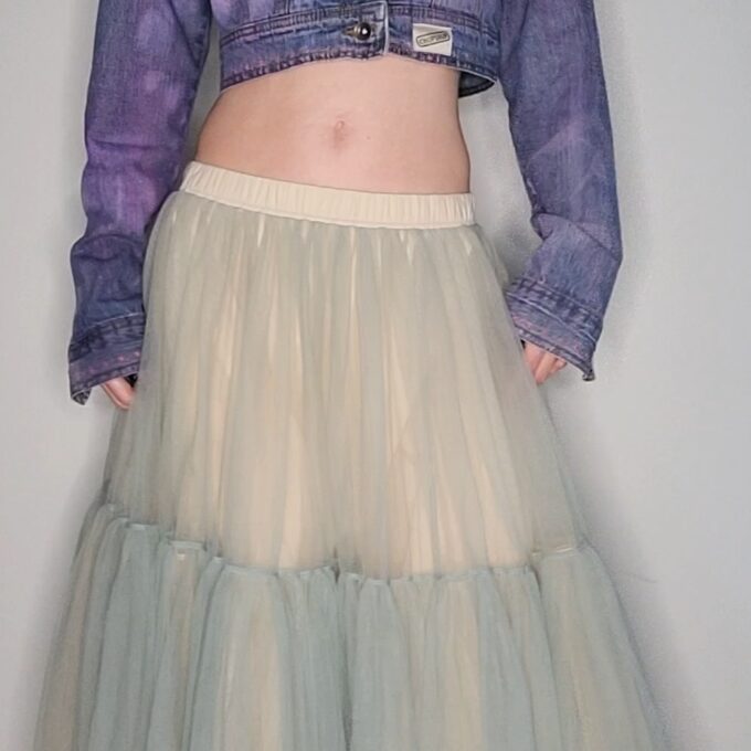 a woman wearing a denim jacket and a tulle skirt.
