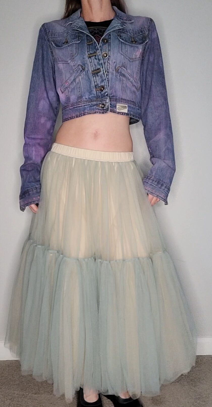 a woman wearing a denim jacket and a tulle skirt.