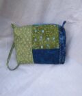 A blue and green fabric wristlet purse with a patchwork pattern in Cottage Core style.