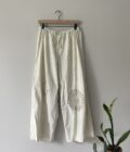 A pair of white pants hanging on a wall.