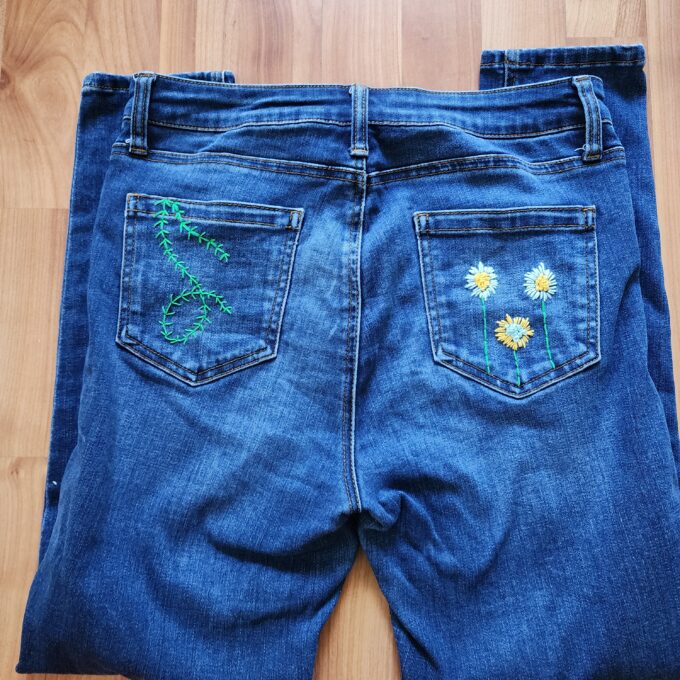 A pair of jeans with embroidered flowers on them.