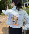 A woman wearing a denim jacket with a tiger on it.