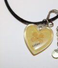 A heart shaped necklace with a yellow flower on it.