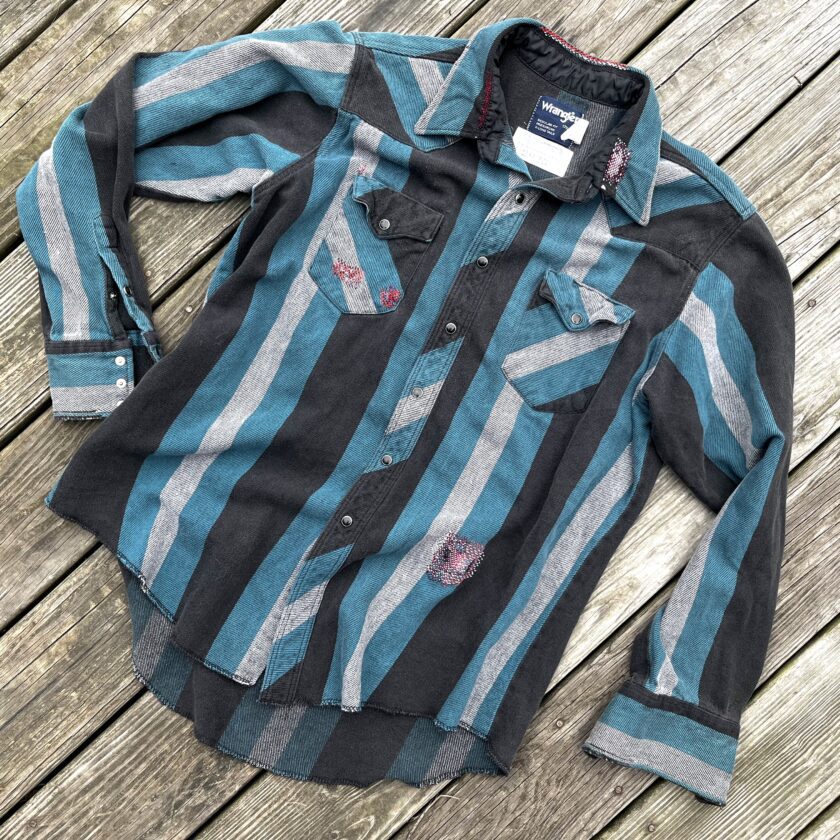 A blue and black striped shirt laying on a wooden floor.