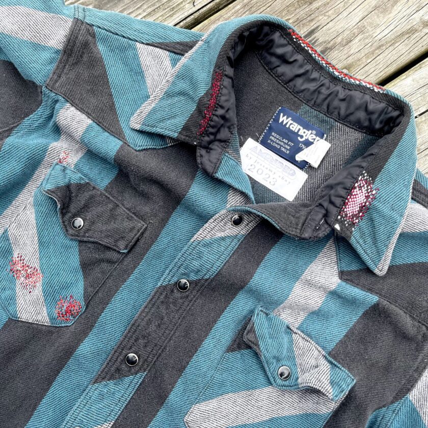 A blue and grey striped shirt on a wooden deck.