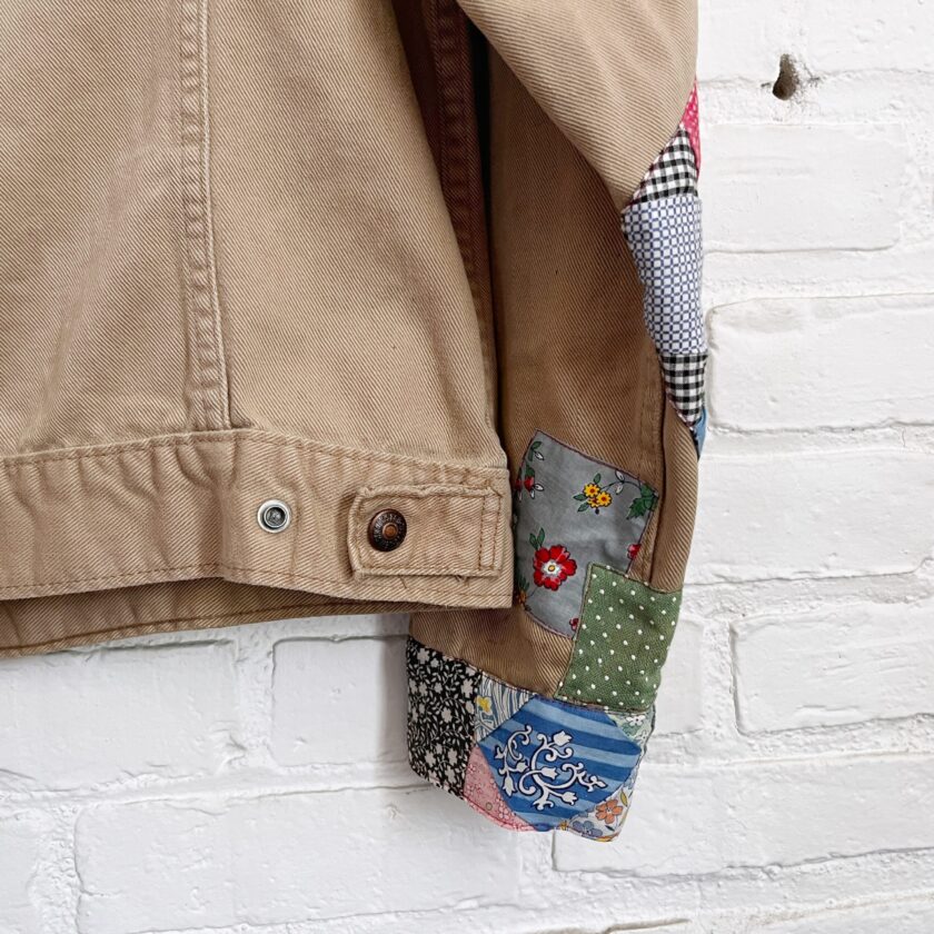 A patchwork jacket hanging on a brick wall.