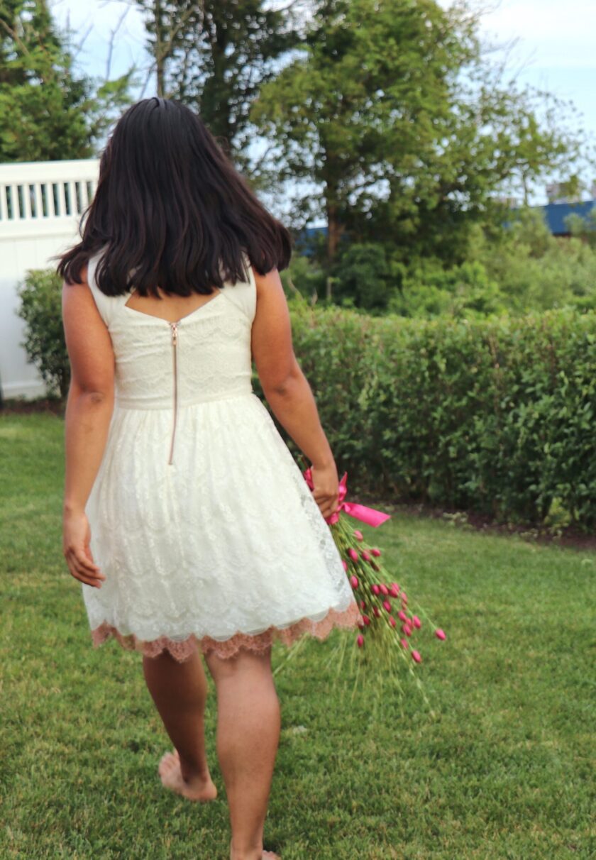 En kvinne i en hvit kjole går gjennom et gressområde.
