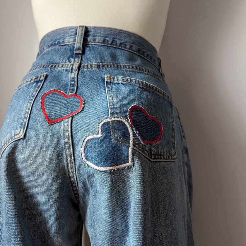 A mannequin wearing a pair of jeans with heart patches.