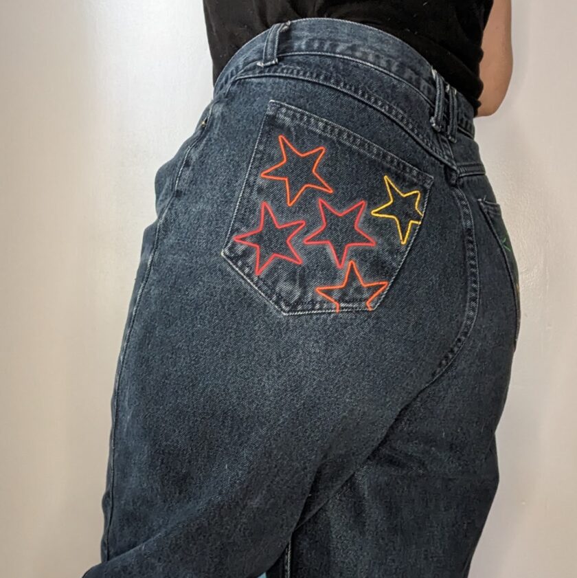 A woman wearing a pair of jeans with stars embroidered on them.