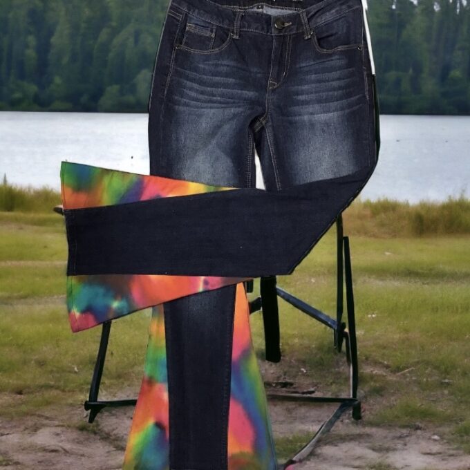 A pair of jeans with a tie dye bell bottom insert on them.