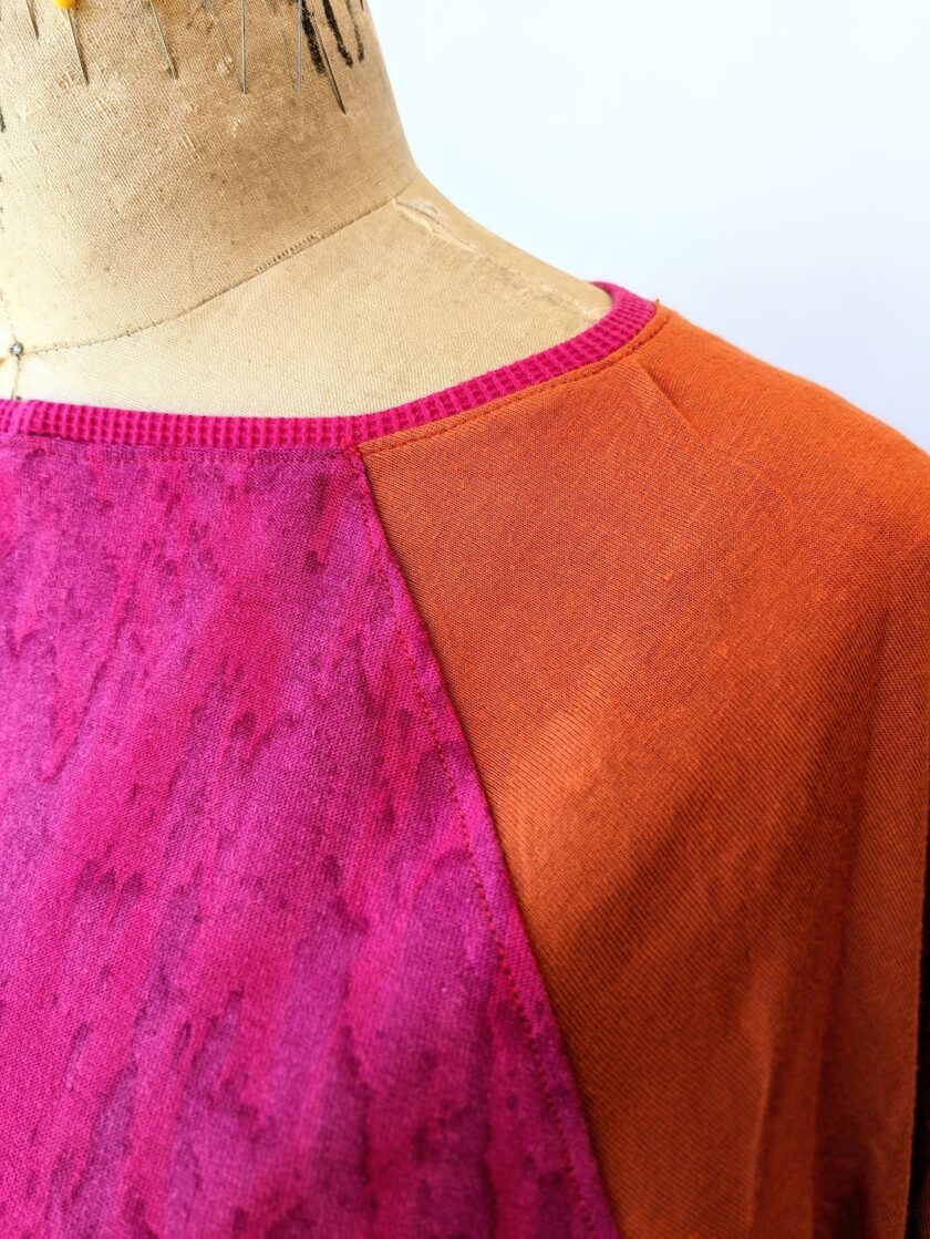 An orange and pink top on a mannequin dummy.
