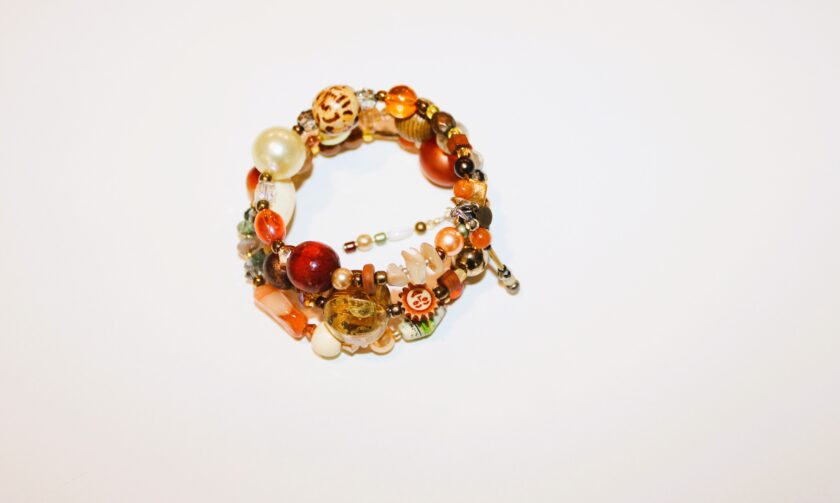 A bracelet with beads and shells on a white surface.