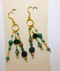 A pair of gold dangling earrings with green and black beads.