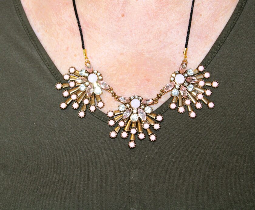 A woman is wearing a necklace with starburst pink beads and crystals.