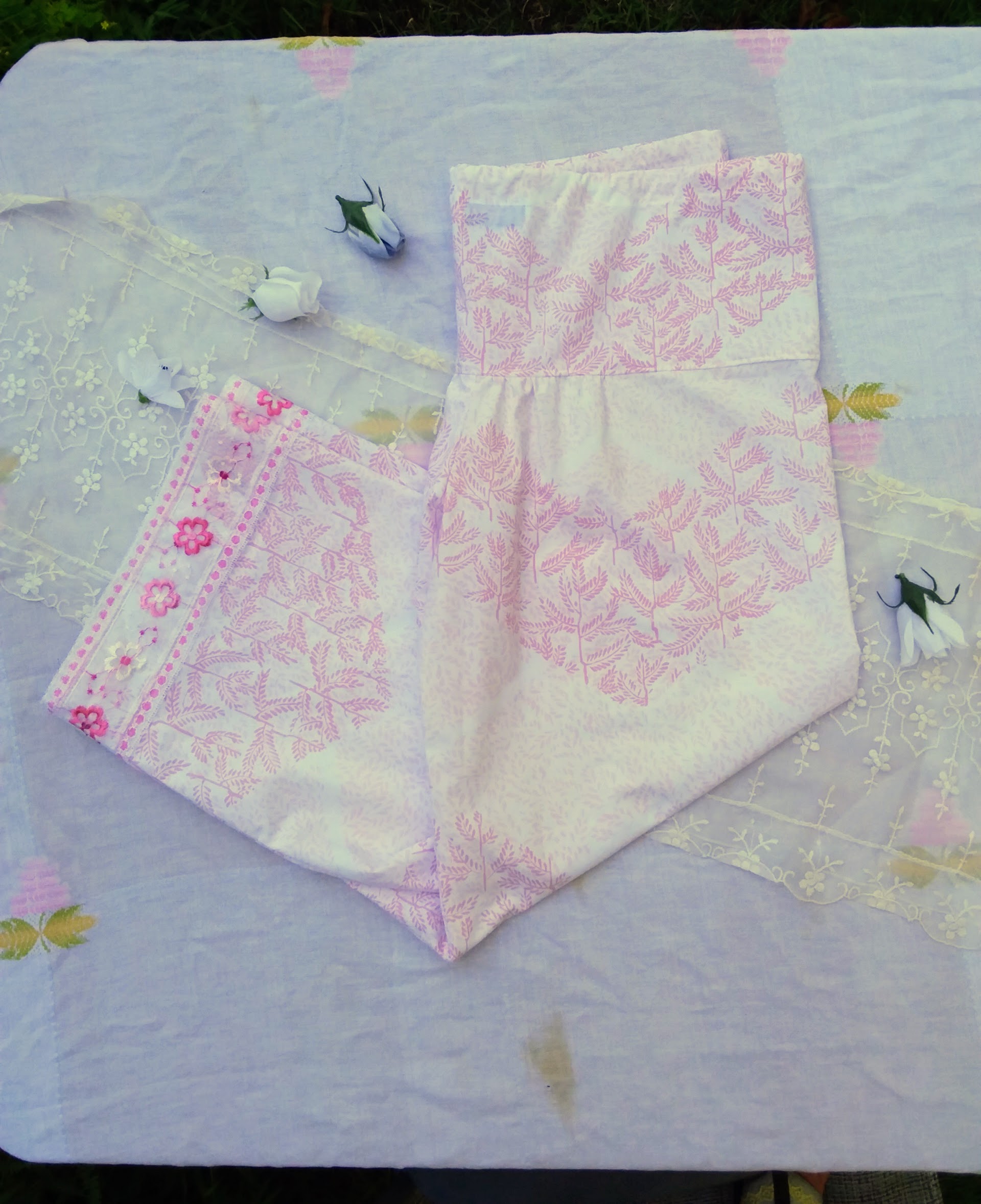 Elegant upcycled pink and white palazzo pants with vintage lace trim laying on a table.