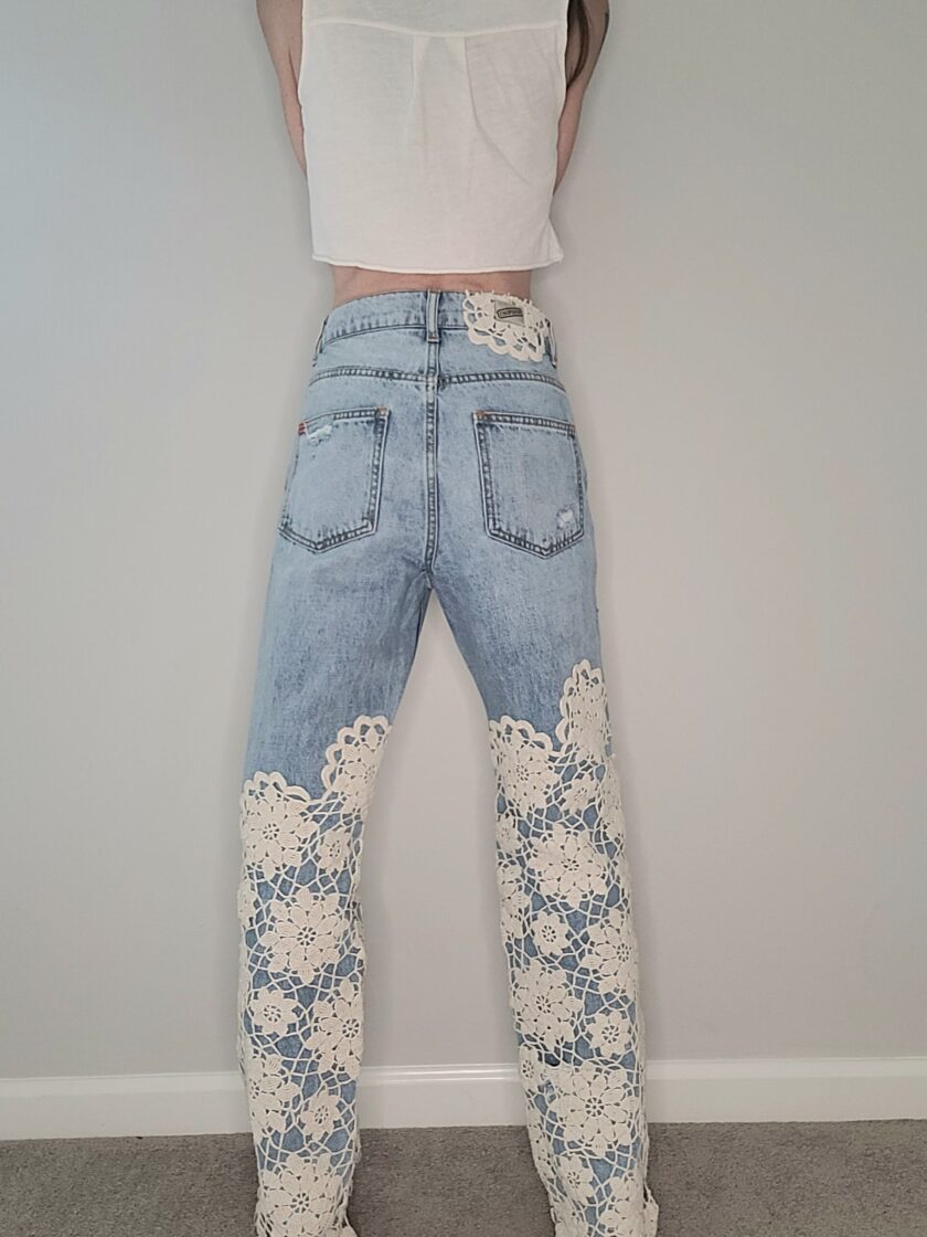 A woman wearing a pair of jeans with lace on them.