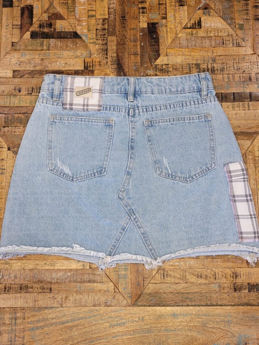 A denim skirt with a plaid patch on it.
