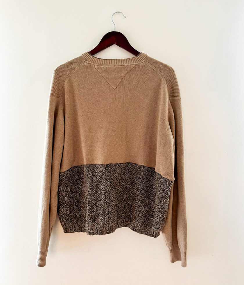 A tan sweater hanging on a wall.