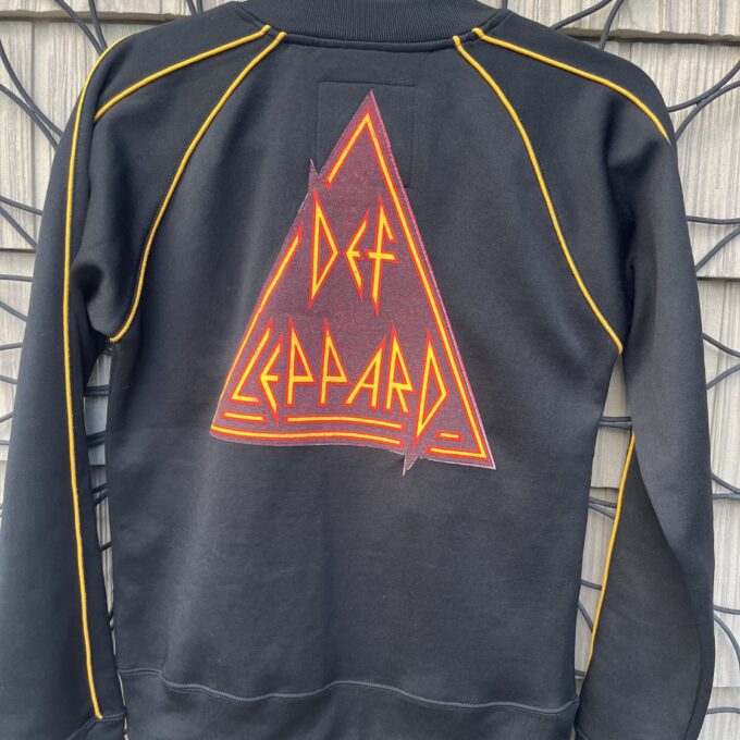 A black sweatshirt with the words def leppard on it.