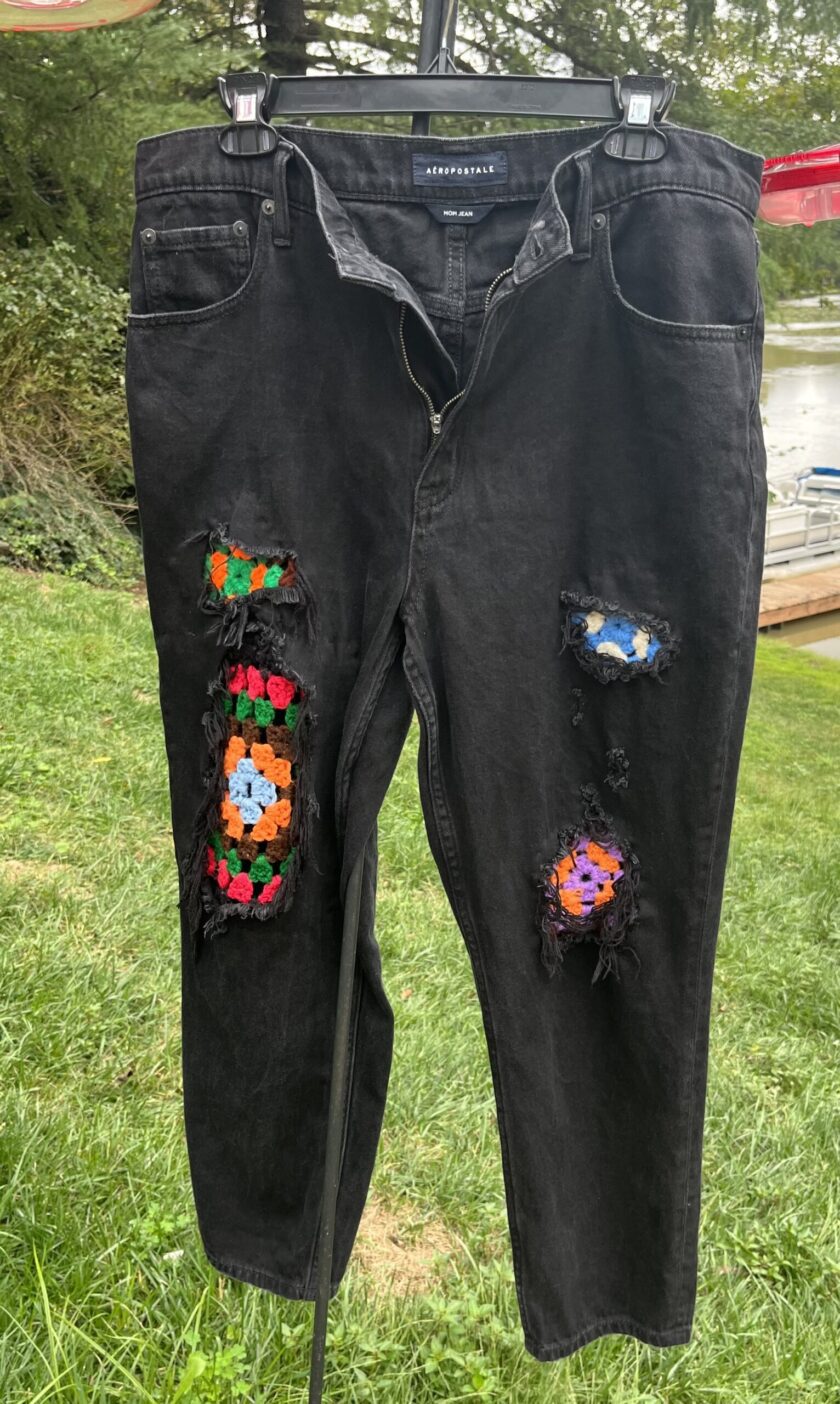 A pair of black jeans with colorful patches on them.
