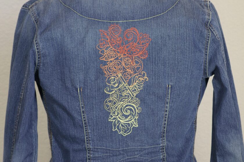 A denim jacket with a colorful design on the back.
