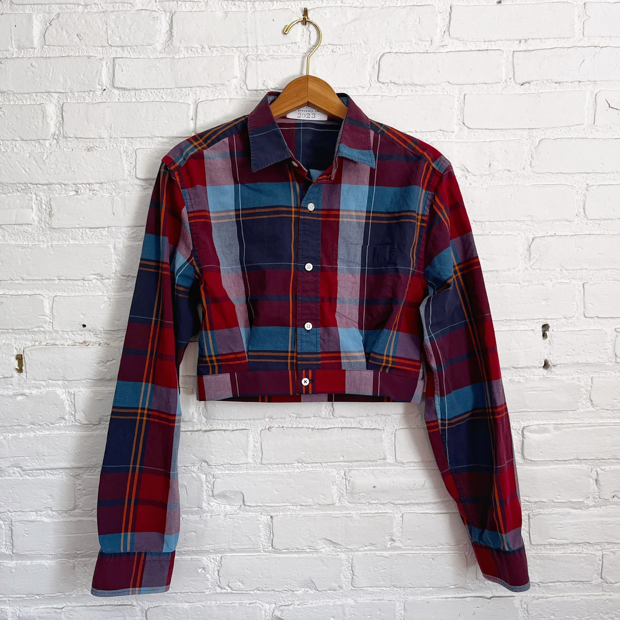 A red and blue plaid shirt hanging on a brick wall.