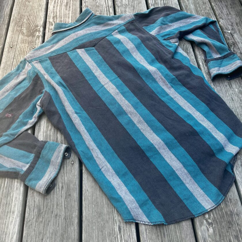 A blue and grey striped shirt on a wooden deck.