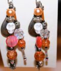 A pair of earrings with orange beads and tassels.