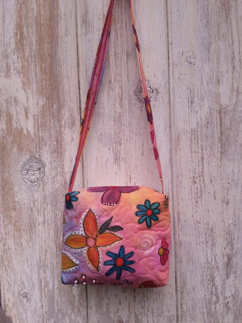 Brightly colored hand painted flowers adorn a hand dyed handbag in pink, orange, blue and yellow