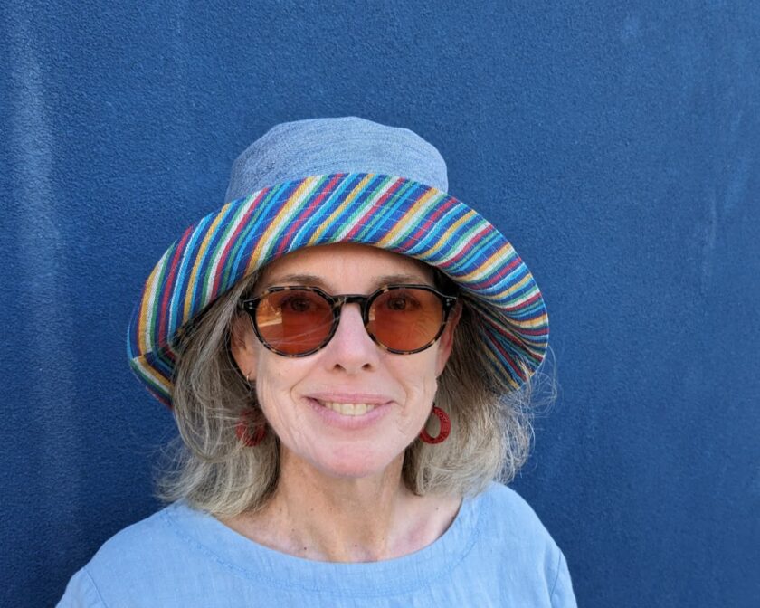 A woman wearing sunglasses and a striped hat.