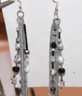 A pair of black and silver earrings hanging on a piece of paper.