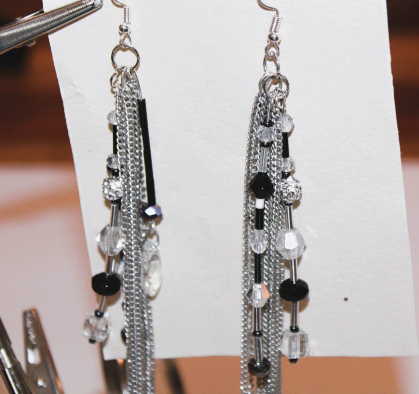A pair of black and silver earrings hanging on a piece of paper.