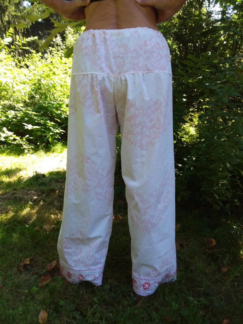 A delicate pink floral design on white palazzo pants made from upcycled textiles