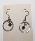 A pair of silver dangle earrings with black stones.