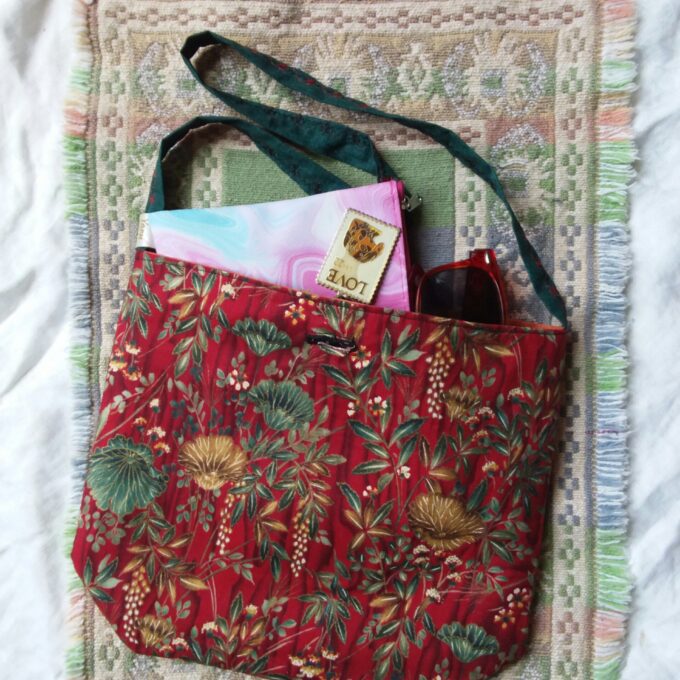 Elegant oriental poppies in gold and green adorn a red fabric hand bag