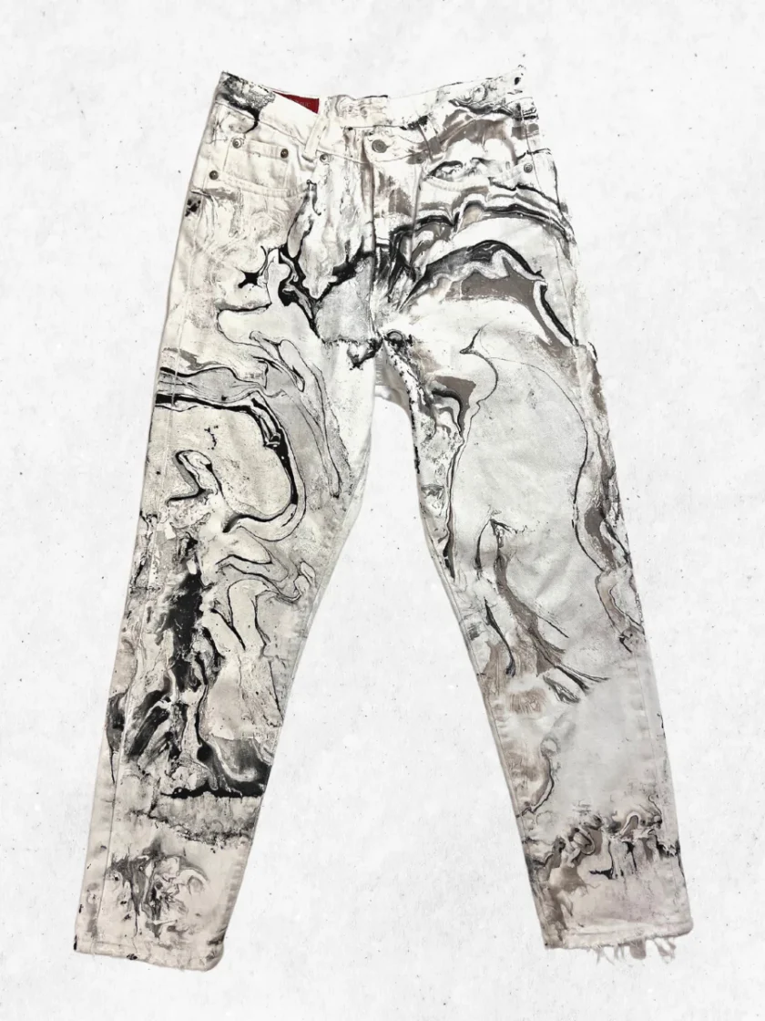 A pair of white jeans with black and white paint on them.
