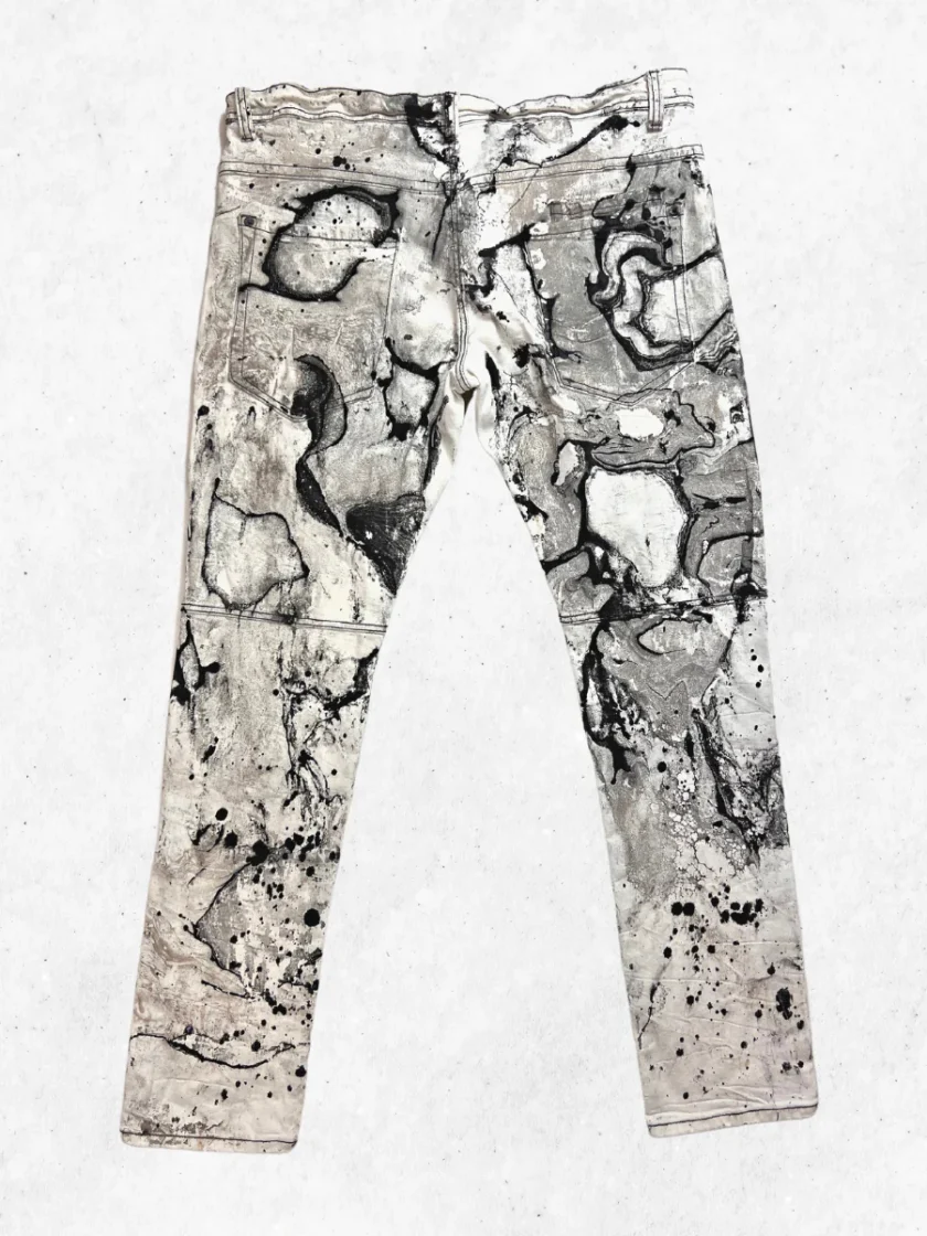 A pair of jeans with black and white paint on them.