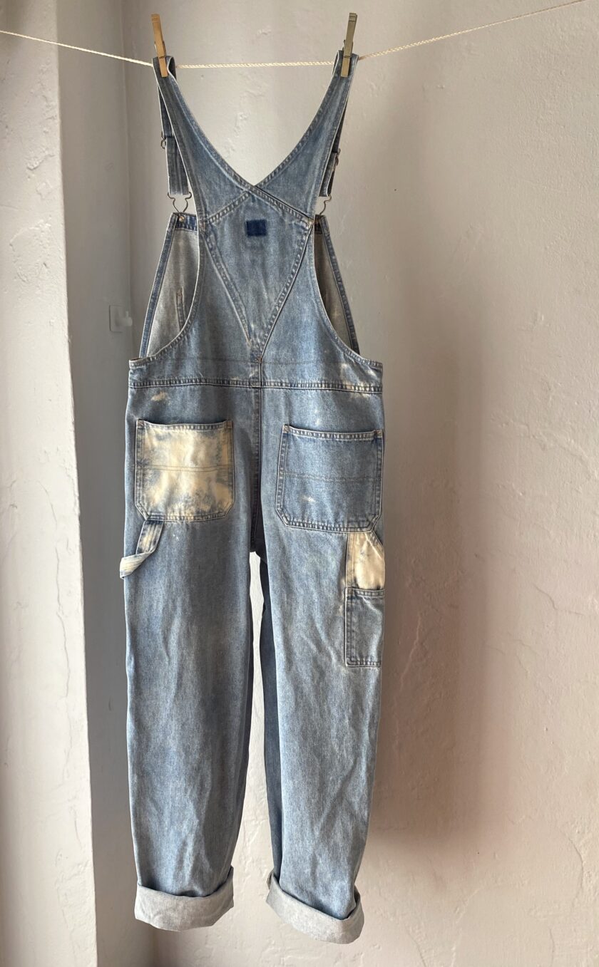 A pair of denim overalls hanging on a clothes line.